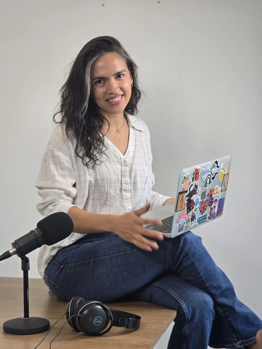 Aura sentada sobre la mesa con su laptop, junto al micrófono