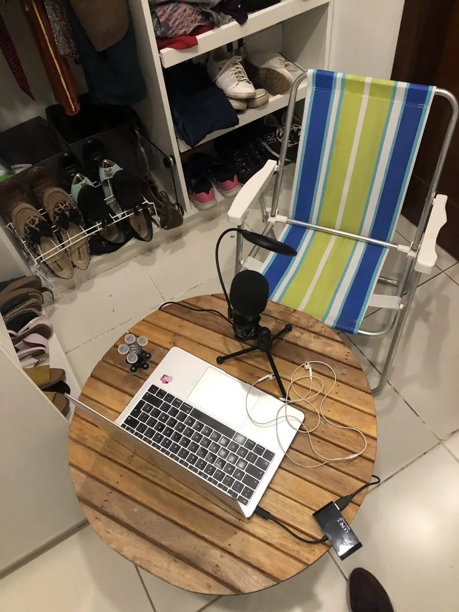 Mesa redonda con laptop y micrófono, y una silla de playa en el vestidor